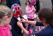Lady pinning badge to young childs jacket. Child is wearing a cycle helmet