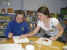 Teacher and a pupil looking down and working at a desk